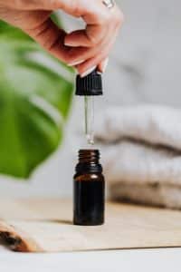 A person is holding a brown bottle with a male reproductive organ enlargement oil.